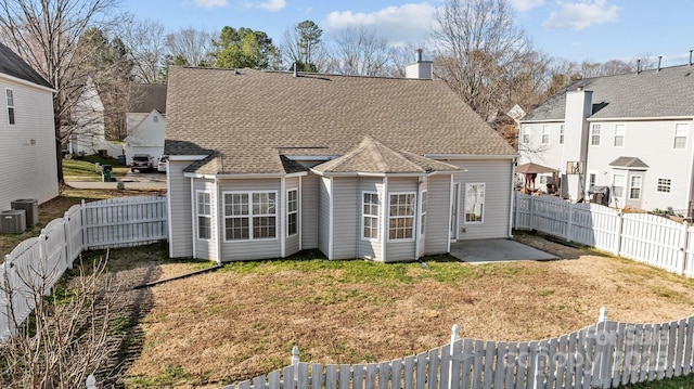 rear view of property featuring a yard, a fenced backyard, a patio, and a shingled roof