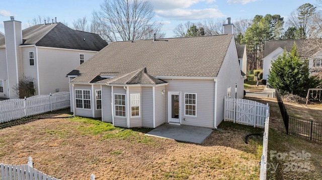 back of property with a chimney, a patio area, a yard, and a fenced backyard