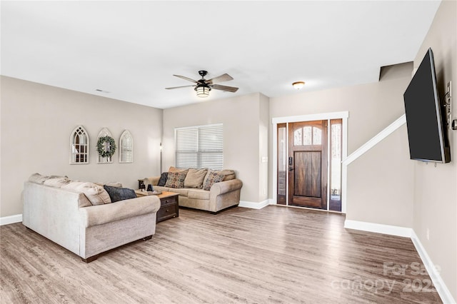 living room with ceiling fan, light wood-style flooring, and baseboards