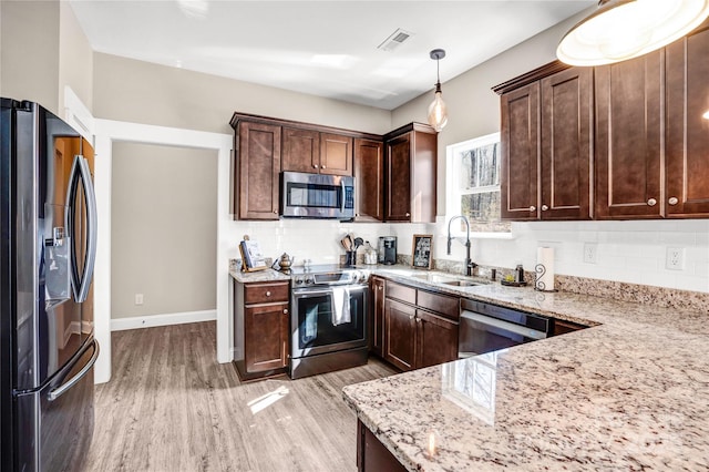 kitchen featuring light stone countertops, visible vents, stainless steel appliances, and a sink