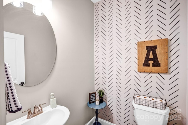 bathroom featuring toilet, baseboards, and a sink