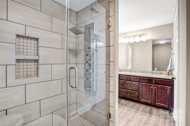 full bathroom with a stall shower, vanity, and wood finished floors