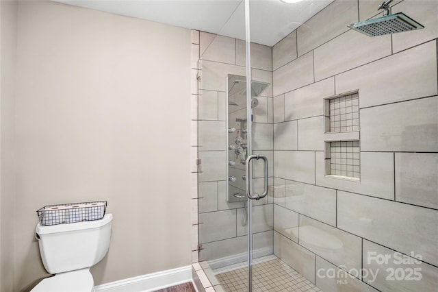 full bath featuring toilet, a stall shower, and baseboards