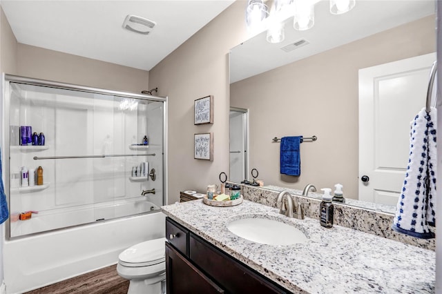 full bathroom with toilet, wood finished floors, vanity, visible vents, and combined bath / shower with glass door