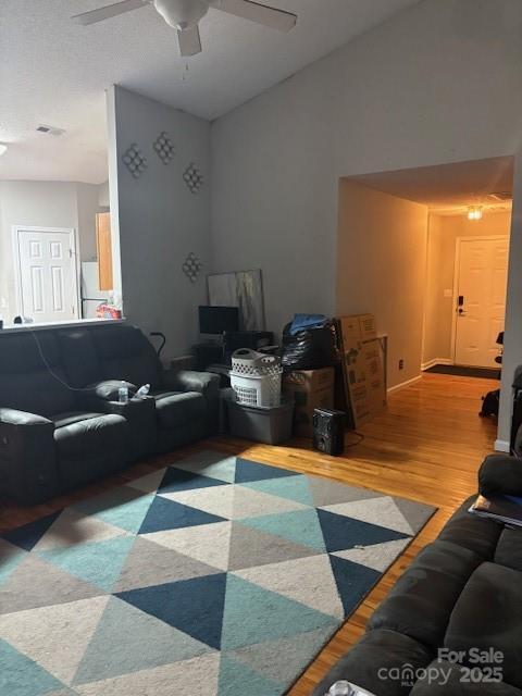 living area featuring lofted ceiling, ceiling fan, and wood finished floors