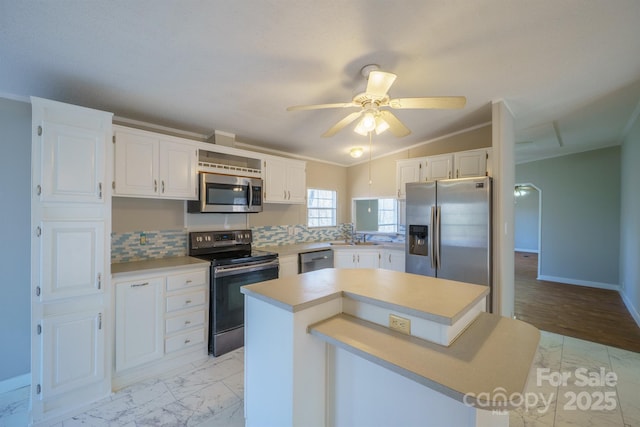 kitchen featuring white cabinetry, appliances with stainless steel finishes, crown molding, and a center island