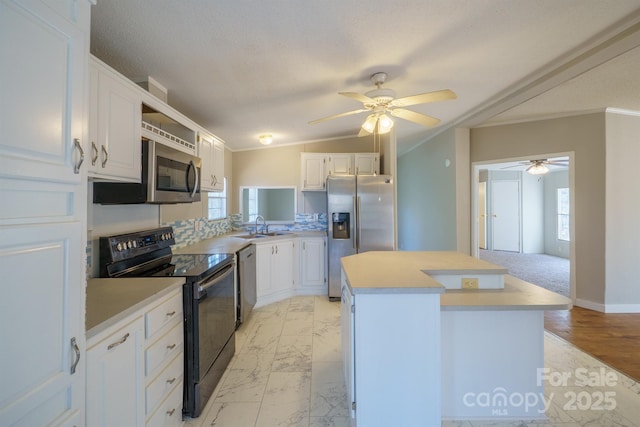 kitchen with appliances with stainless steel finishes, vaulted ceiling, a kitchen island, sink, and white cabinetry