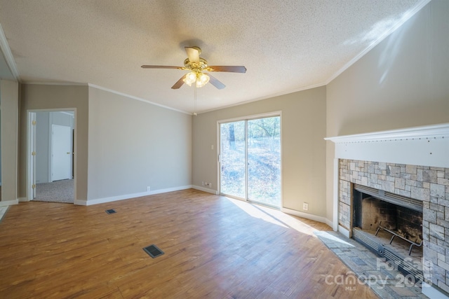 unfurnished living room with light wood-type flooring, a stone fireplace, and ornamental molding