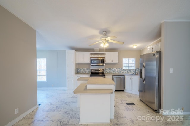 kitchen featuring a kitchen island, sink, ceiling fan, appliances with stainless steel finishes, and white cabinets