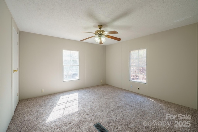 carpeted empty room featuring ceiling fan and a textured ceiling