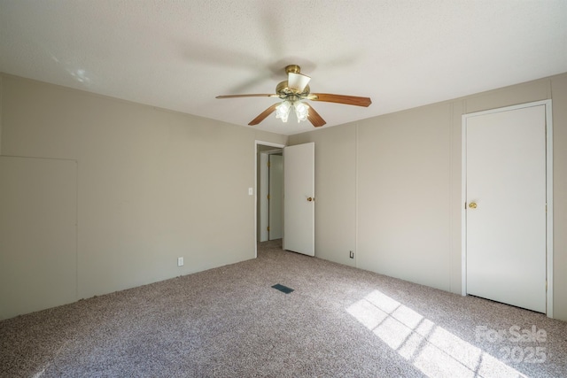 unfurnished bedroom featuring ceiling fan, light carpet, and a textured ceiling