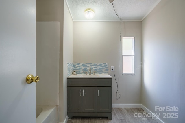 bathroom featuring hardwood / wood-style flooring, vanity, a textured ceiling, and backsplash