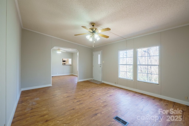 empty room with wood-type flooring, ceiling fan, crown molding, and a textured ceiling