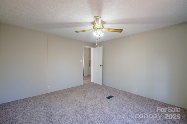 empty room with ceiling fan, carpet floors, and a textured ceiling