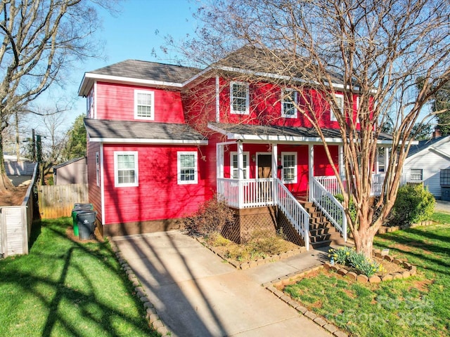 view of front of house with covered porch, a front yard, and fence