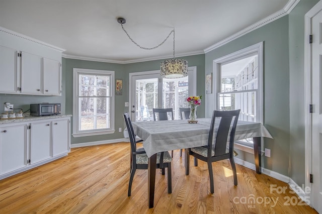 dining room with plenty of natural light, light wood-style floors, and ornamental molding