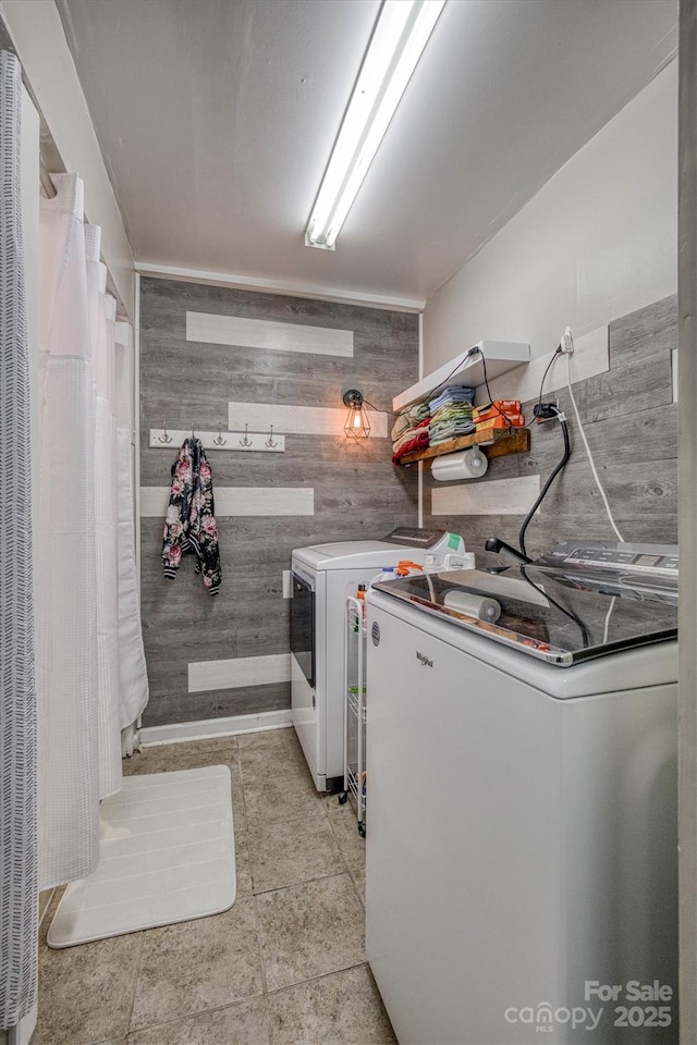 laundry room featuring wooden walls, washing machine and dryer, and laundry area