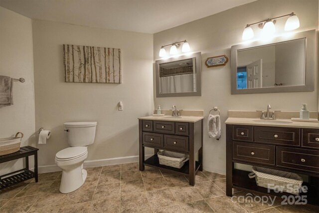 bathroom with baseboards, toilet, and vanity