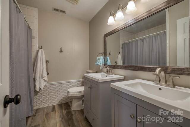 bathroom featuring a sink, visible vents, toilet, and wood finished floors