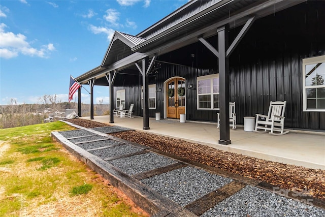 entrance to property with a patio area, french doors, and board and batten siding