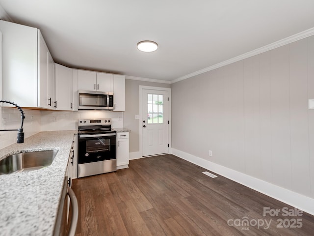 kitchen with a sink, white cabinets, appliances with stainless steel finishes, dark wood finished floors, and crown molding