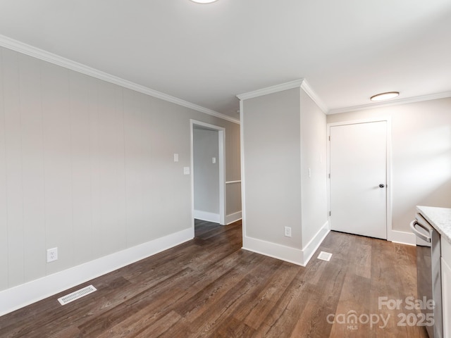 spare room featuring ornamental molding, visible vents, baseboards, and wood finished floors