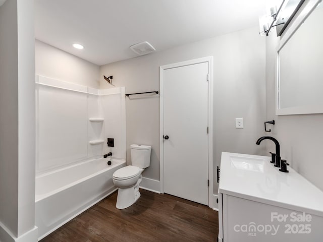 bathroom featuring visible vents, toilet, wood finished floors, vanity, and shower / washtub combination