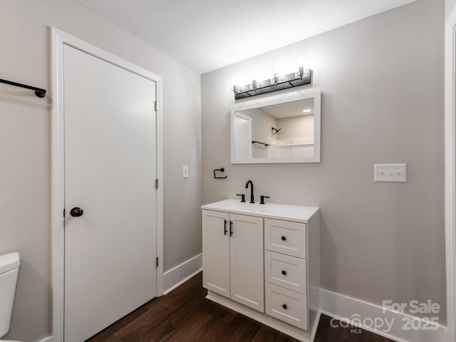 bathroom with baseboards, vanity, toilet, and wood finished floors