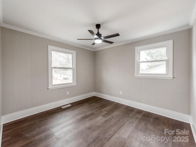 unfurnished room with a wealth of natural light, dark wood-style flooring, visible vents, and baseboards