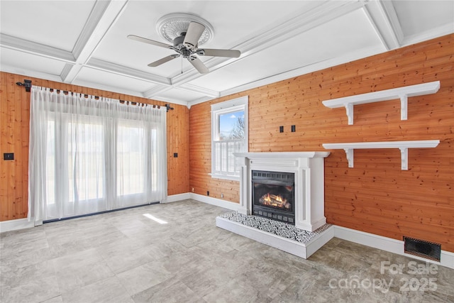 unfurnished living room with coffered ceiling, visible vents, baseboards, beam ceiling, and a glass covered fireplace