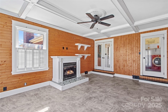 unfurnished living room featuring wooden walls, coffered ceiling, beamed ceiling, and french doors