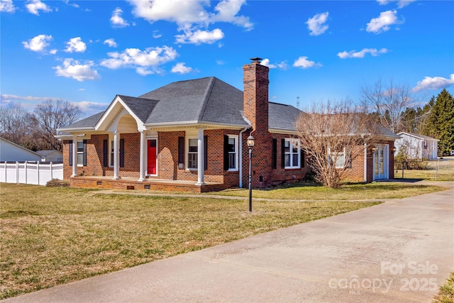 view of front of house with brick siding, a chimney, roof with shingles, fence, and a front yard