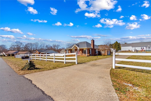 view of front of house featuring a fenced front yard, brick siding, a chimney, driveway, and a front lawn