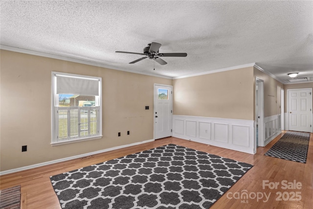 foyer entrance with ceiling fan, visible vents, crown molding, and wood finished floors