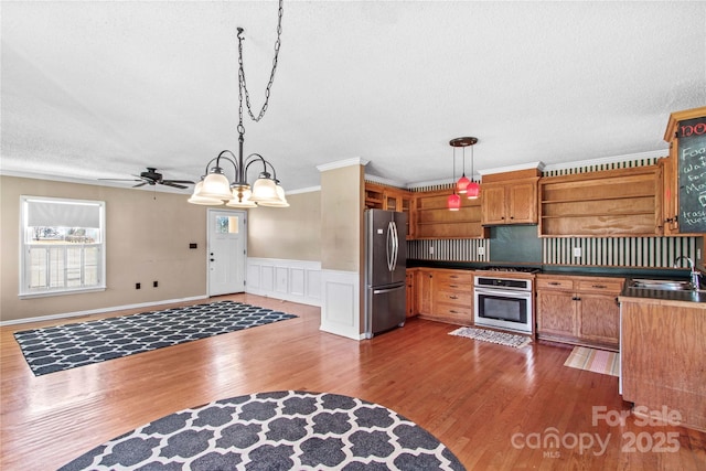 kitchen featuring wood finished floors, open shelves, appliances with stainless steel finishes, and a sink