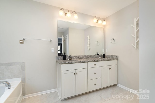 full bath featuring double vanity, a sink, tile patterned flooring, baseboards, and a bath