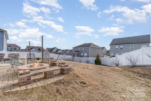 view of yard featuring a patio area, a fenced backyard, a residential view, and a fire pit