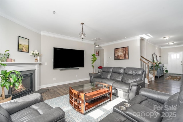 living room with baseboards, a glass covered fireplace, stairway, wood finished floors, and crown molding