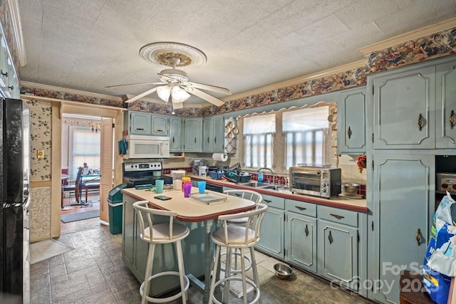 kitchen featuring sink, a breakfast bar area, crown molding, a textured ceiling, and ceiling fan