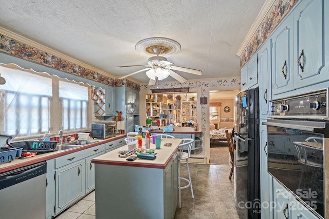 kitchen featuring a breakfast bar, sink, a center island, ceiling fan, and stainless steel appliances