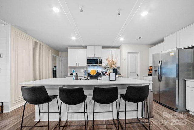 kitchen featuring white cabinetry, stainless steel appliances, light hardwood / wood-style floors, and an island with sink