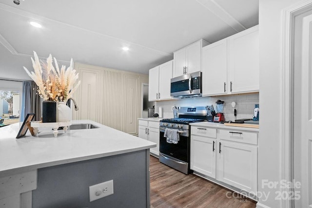 kitchen with dark wood-type flooring, sink, white cabinetry, tasteful backsplash, and appliances with stainless steel finishes