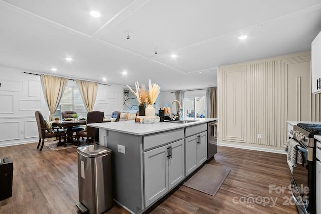 kitchen with sink, gray cabinetry, a center island with sink, appliances with stainless steel finishes, and dark hardwood / wood-style floors