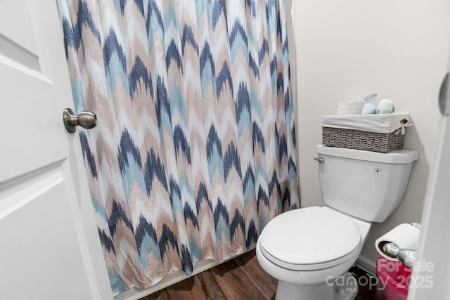 bathroom with hardwood / wood-style flooring, toilet, and curtained shower