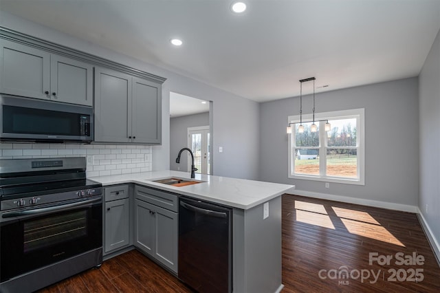 kitchen featuring appliances with stainless steel finishes, light stone counters, sink, dark hardwood / wood-style floors, and kitchen peninsula