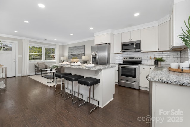 kitchen featuring decorative backsplash, an island with sink, light stone counters, dark wood-type flooring, and stainless steel appliances