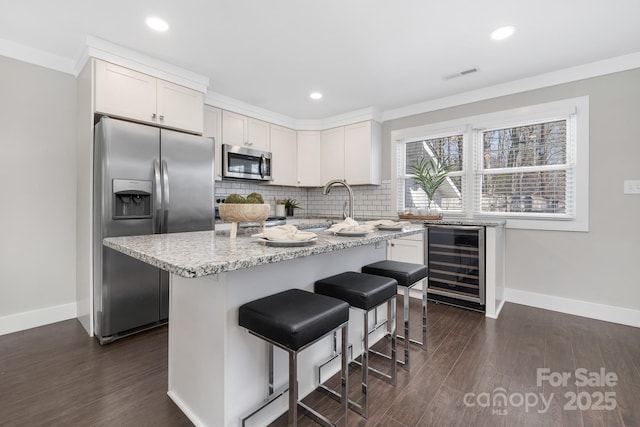 kitchen featuring beverage cooler, visible vents, decorative backsplash, light stone counters, and stainless steel appliances