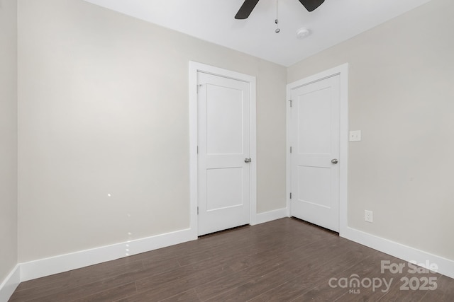 unfurnished bedroom with a ceiling fan, baseboards, and dark wood-style flooring