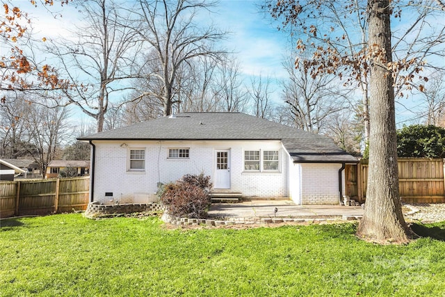 rear view of property featuring fence, a lawn, and brick siding