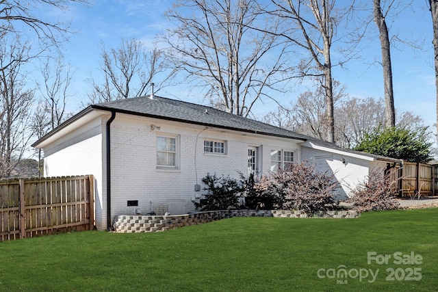 back of property featuring crawl space, brick siding, a yard, and fence